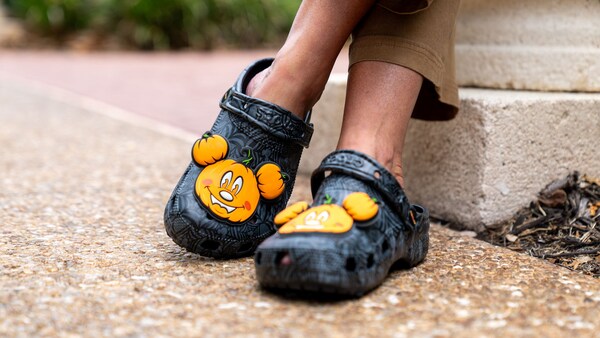 A Guest wearing a pair of Crocs decorated with big Mickey Mouse shaped pumpkin charms