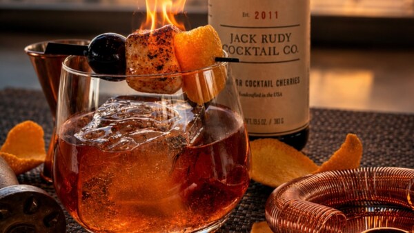 A cocktail with a toasted garnish and the sunset in the distance