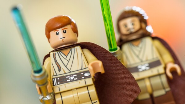 Two Lego minifigures from Star Wars holding light sabers