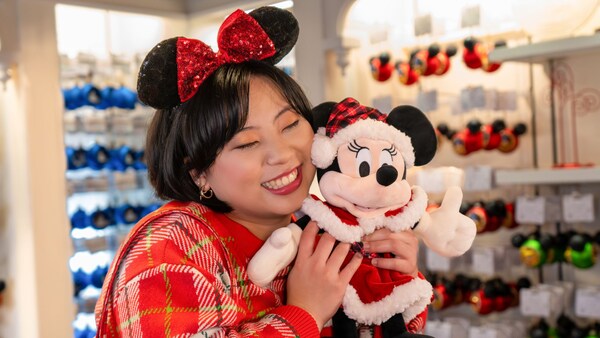 Un Visitante abrazando un peluche de Minnie Mouse vestida de Santa