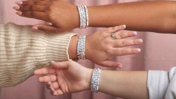 Three hands adorned with friendship bracelets 