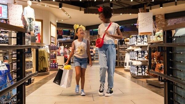 A mother and her daughter walking around World of Disney carrying shopping bags