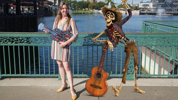 Una mujer con una guitarra de utilería posa junto a Hector, de la película Coco, y su guitarra cerca de Lake Buena Vista  