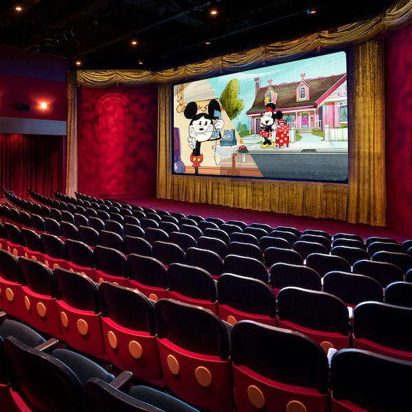An empty theater with a film featuring Mickey and Minnie Mouse projected on the movie screen