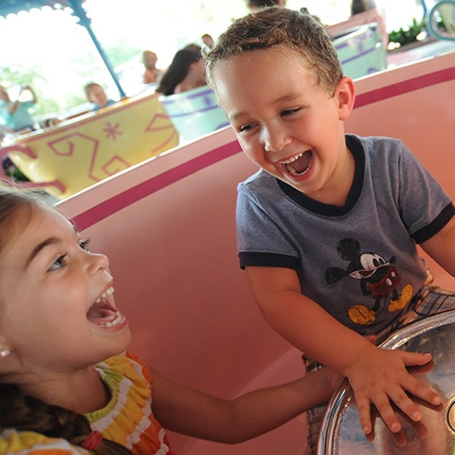 Two children laughing while riding Mad Tea Party