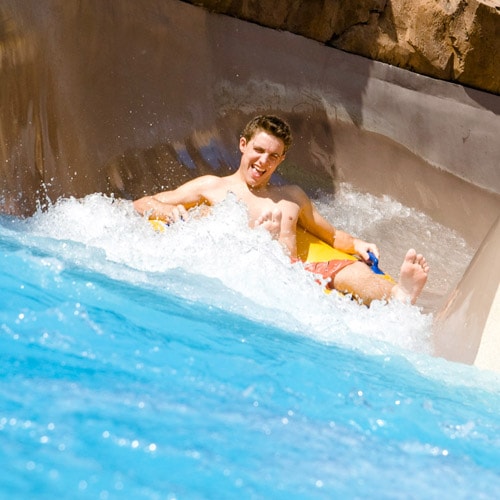 A Guest sitting in an inner tube as it splashes into the water at the end of a water slide