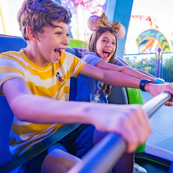 Two young Guests smiling while riding the Alien Swirling Saucers attraction in Toy Story Land