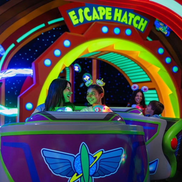 A mother and daughter smiling as they ride Buzz Lightyear's Space Ranger Spin at Magic Kingdom park