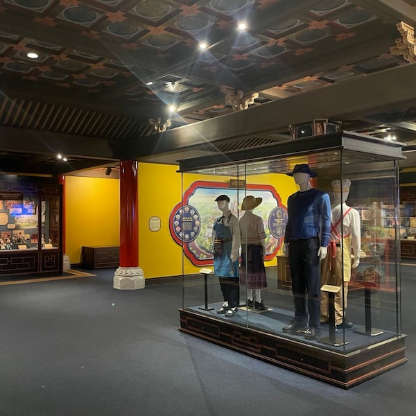 The interior of House of Whispering Willows at Shanghai Disney Resort featuring display cases with Disney artwork and 4 mannequins in vintage costumes