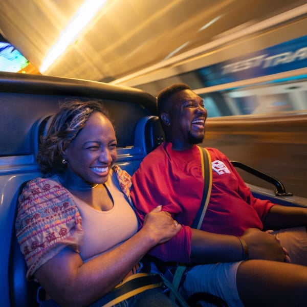 A couple smiling as they ride in a fast moving car in Test Track at Epcot
