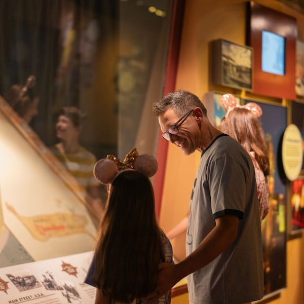 A father and daughter looking at a Walt Disney World Resort map in the Walt Disney Presents gallery at Disney’s Hollywood Studios
