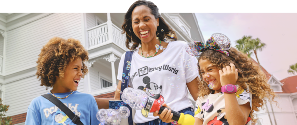 Una madre y dos niños se ríen y juegan con las varillas de burbujas de Mickey Mouse