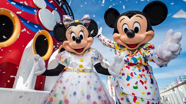 Mickey Mouse y Minnie rodeados de papel picado mientras saludan desde la cubierta de un crucero
