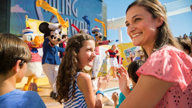 A woman and 2 small children smiling and clapping their hands during the Sailing Away Deck Party