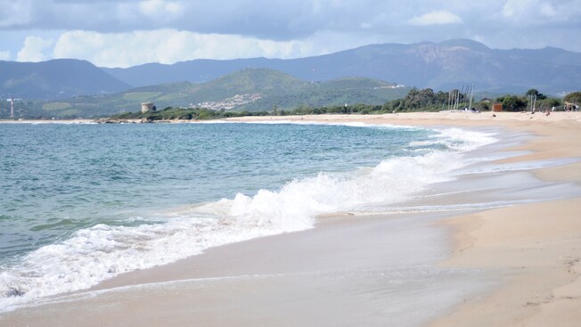 Sea waves breaking on a shore surrounded by verdant mountains