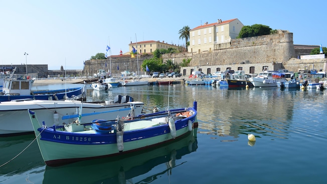 Fishing boats docked in a harbor next to a fortification wall