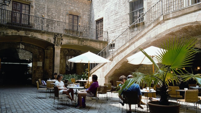 Visitantes cenando en un café al aire libre situado en un patio centenario Visitantes cenando en un café al aire libre situado en un patio centenario
