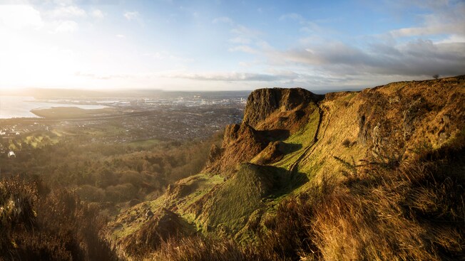 La ciudad de Belfast al pie de un bosque y una colina rocosa