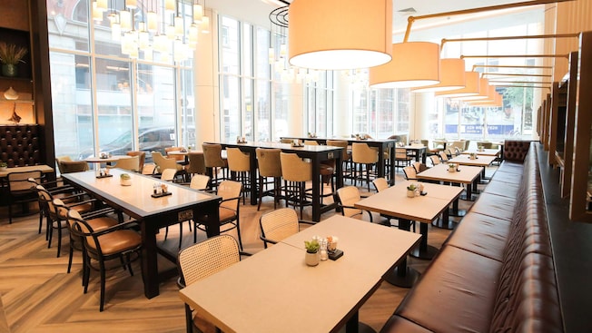 Um restaurante contemporâneo com janelas do chão ao teto, candelabros, mesas e cadeiras Um restaurante contemporâneo com janelas do chão ao teto, candelabros, mesas e cadeiras