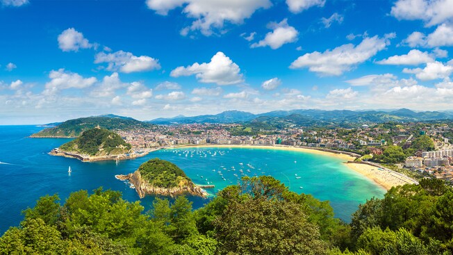 Verdant mountains surrounding a bay filled with boats and lined with late 19th century architecture