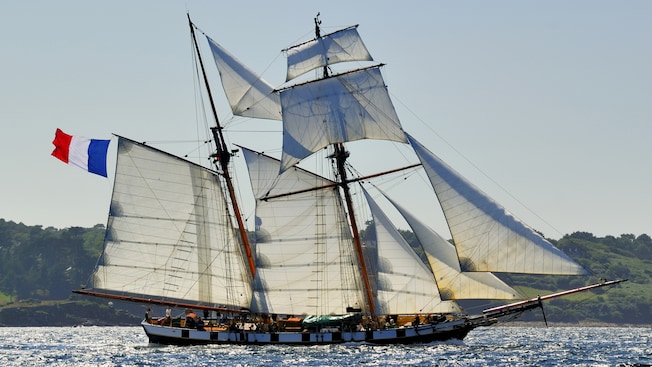 A tall ship filled with passengers and crew sailing through the waters A tall ship filled with passengers and crew sailing through the waters