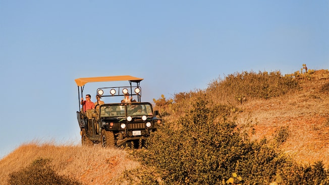 An open air Hummer filled with passengers traveling through rugged terrain An open air Hummer filled with passengers traveling through rugged terrain