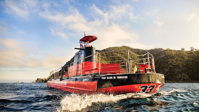 A captain piloting a semi submersible boat next to an island A captain piloting a semi submersible boat next to an island