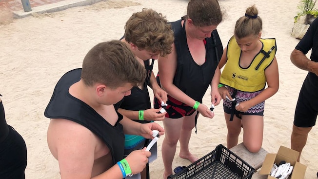 A group of young people on a beach checking tubes of water with P H sticks A group of young people on a beach checking tubes of water with P H sticks