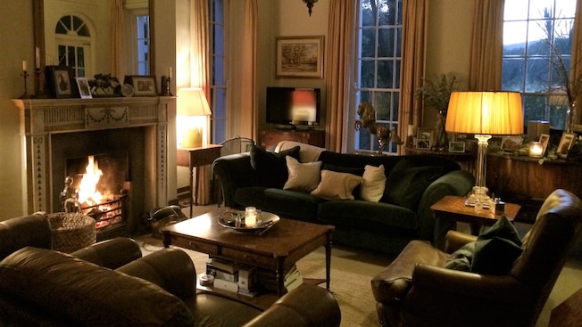 A cozy living room with a burning fireplace, 2 overstuffed chairs, a sofa and artwork A cozy living room with a burning fireplace, 2 overstuffed chairs, a sofa and artwork