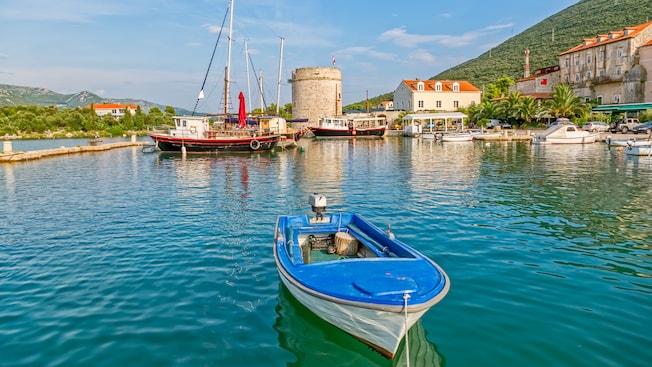 Um porto tranquilo com pequenos barcos de pesca perto de uma vila medieval Um porto tranquilo com pequenos barcos de pesca perto de uma vila medieval