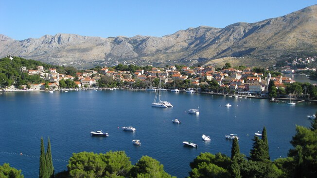 Sailboats moored in the water next to a mountainous seaside village