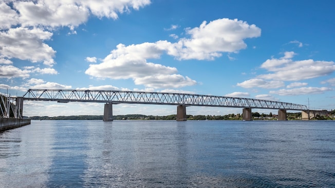 A bridge stretches across a body of water with hills in the background A bridge stretches across a body of water with hills in the background