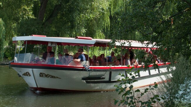 Guests enjoying a boat tour on a tree lined river