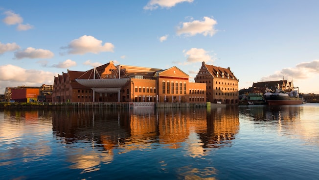A large neo Gothic brick building with a curviliner awning at the water's edge A large neo Gothic brick building with a curviliner awning at the water's edge
