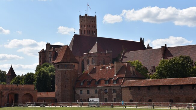 A large brick castle built in the Gothic style with defensive walls and towers