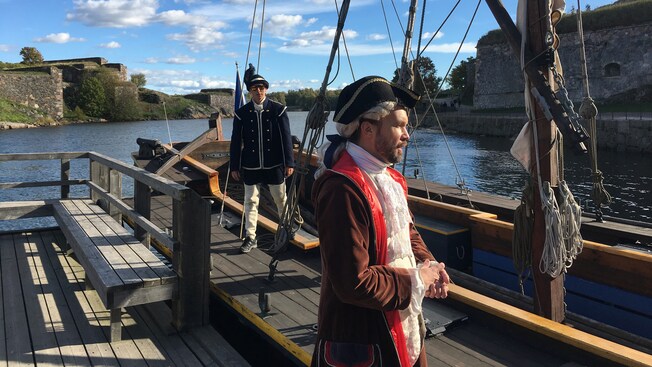 2 men dressed as 18th century sailors on a long ship