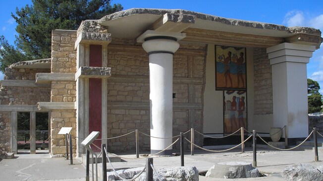 The ancient ruins of a columned building with frescoes painted on one of its walls