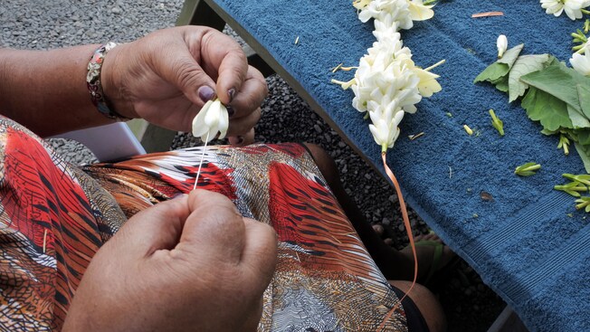 Un par de manos de mujer enhebrando flores