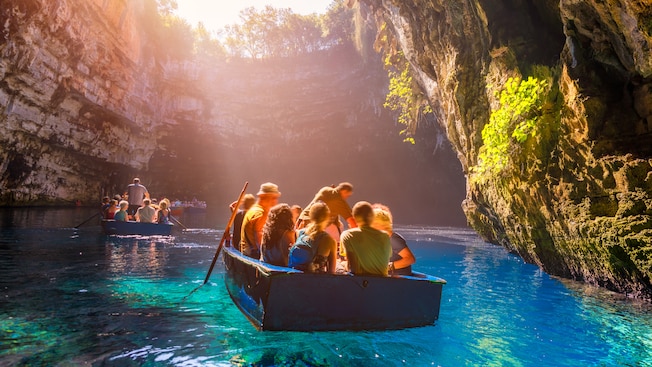2 boats filled with Guests explore Melissani Caves as sunlight pours in from high above 2 boats filled with Guests explore Melissani Caves as sunlight pours in from high above