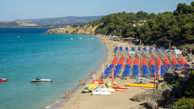 Camastros, sombrillas y botes rodean una franja de costa en la Playa de Makris Camastros, sombrillas y botes rodean una franja de costa en la Playa de Makris