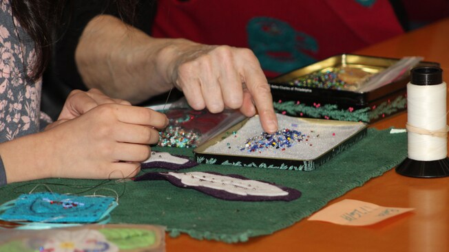 The hand of an older woman pointing out a variety beads to a child