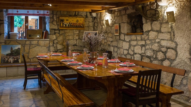 A table set for 10 in a rustic dining area with stone walls