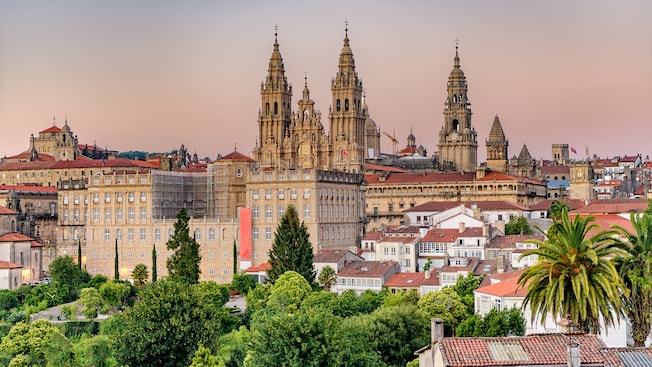 An ornate Gothic cathedral with 3 steeples towering over a European city An ornate Gothic cathedral with 3 steeples towering over a European city