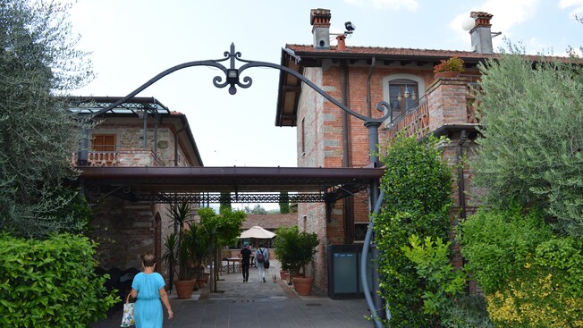 Um convidado caminhando sob a entrada em arco de ferro fundido de uma fazenda rústica