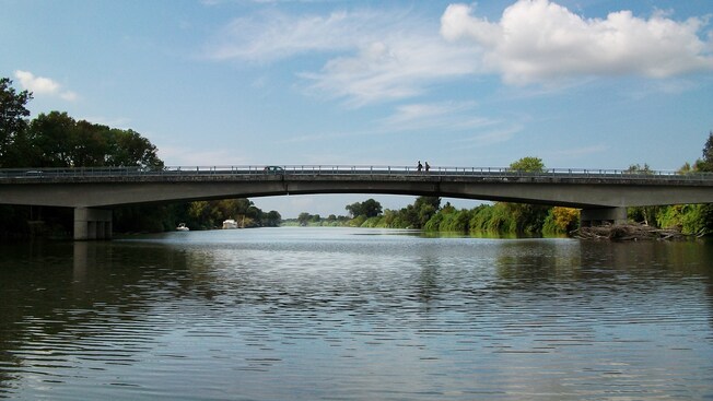 A bridge over a calm river lined with greenery