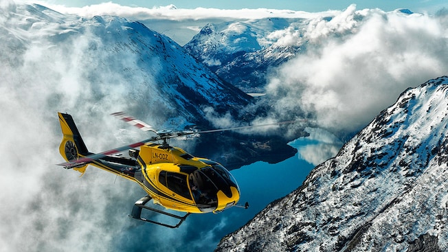 A helicopter soars above clouds, mountains and a lake A helicopter soars above clouds, mountains and a lake