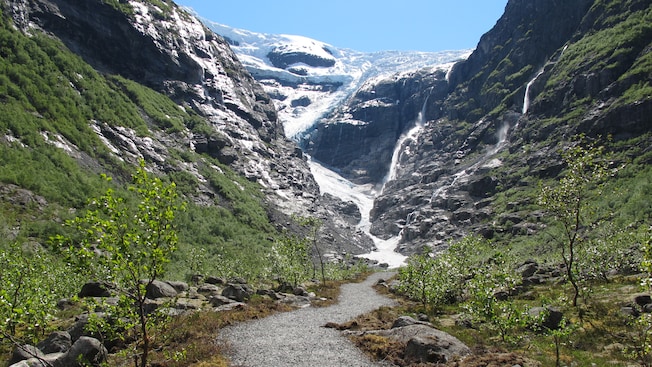 A walking trail through the mountains with the Kjenndalen Glacier in the background A walking trail through the mountains with the Kjenndalen Glacier in the background