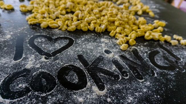 The words I love cooking written into some flour scattered on a cookie sheet with gnocchi