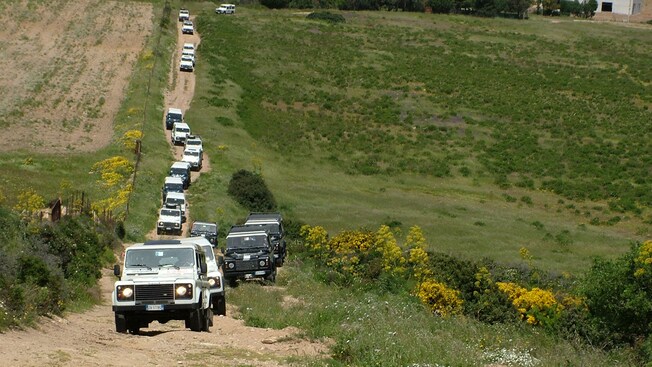 Uma caravana de Jipes viajando por um campo acidentado