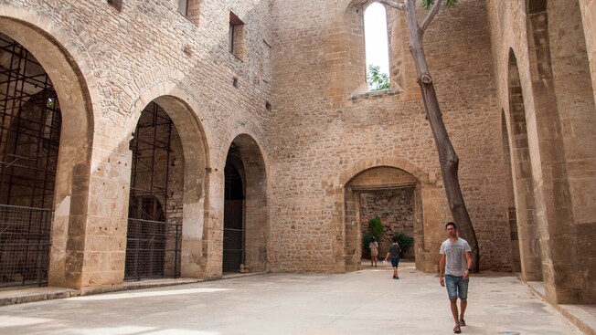 A man walks through a large, open-air courtyard made of rocks and concrete